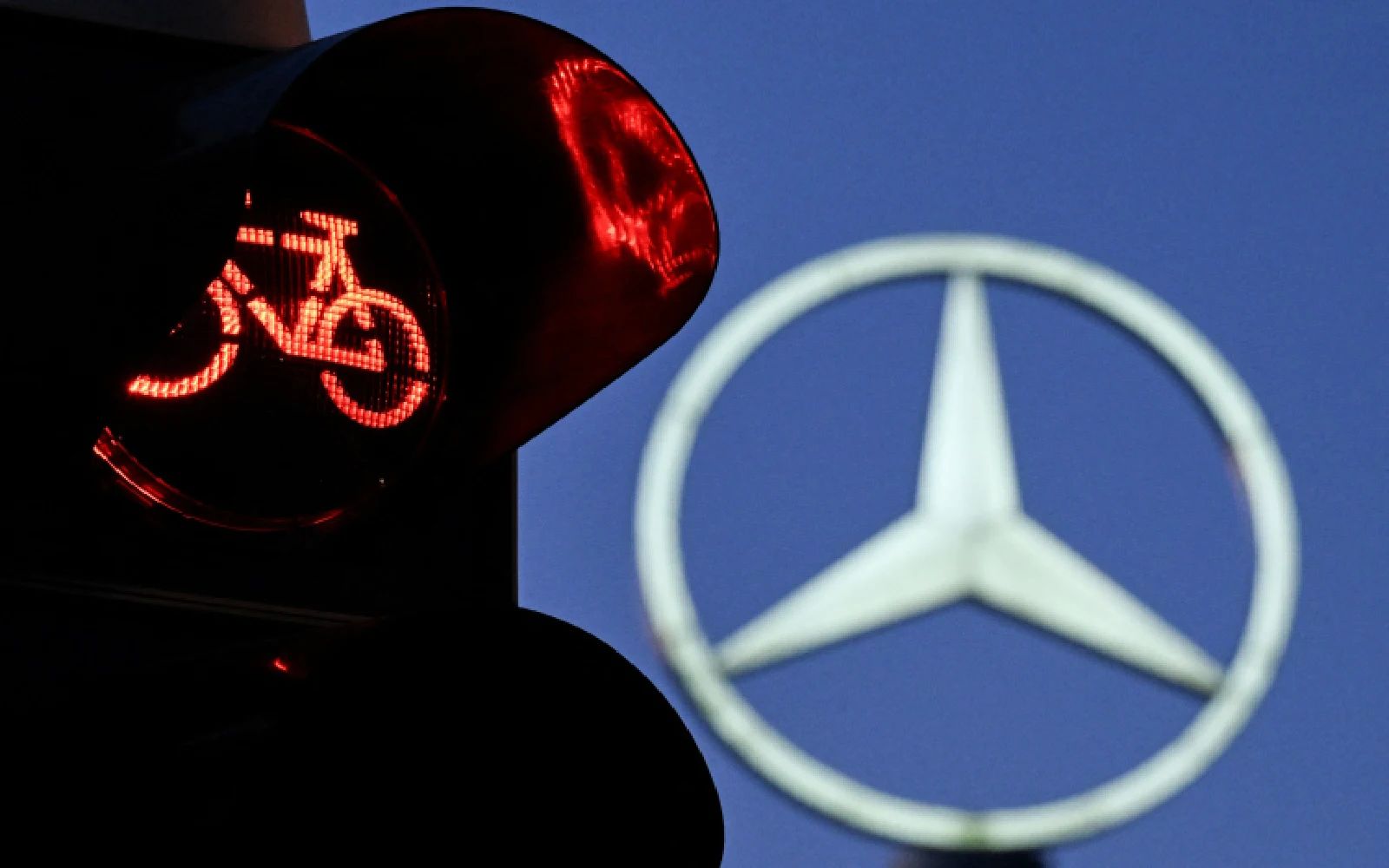 A traffic light for cyclists is pictured in front of a giant logo of German automotive brand Mercedes-Benz is seen atop a Mercedes dealership in Offenbach, western Germany, on April 29, 2026. German premium automaker Mercedes-Benz said on April 29 its first-quarter profit fell by almost a fifth as cutthroat competition in China shakes the world's carmakers.