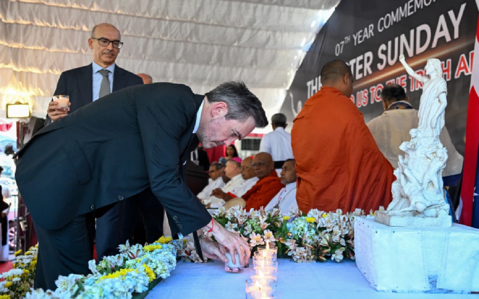 United Nations Resident Coordinator in Sri Lanka, Marc-André Franche (C) places candles as he pays homage to the victims of 2019 Easter Sunday bombings, during its 7th anniversary at the St. Anthony's Church in Colombo on April 21, 2026. Seven years after Sri Lanka's Easter Sunday bomb blasts that killed 279 people, survivors still bear deep physical and emotional scars, compounded by the failure of successive governments to deliver justice. Coordinated suicide bombings targeted three churches and three luxury hotels on April 21, 2019.