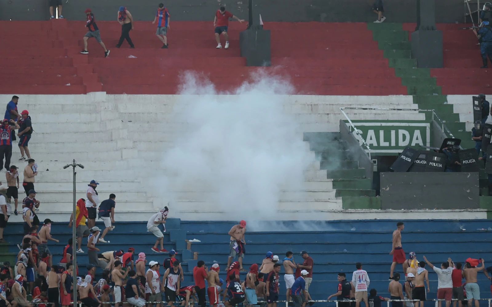 Fans of Cerro Porteno clash with police officers during the Paraguayan tournament football match between Olimpia and Cerro Porteno at the Defensores del Chaco stadium in Asuncion on April 19, 2026. Several people were injured and at least a hundred were arrested following incidents that occurred during the Paraguayan football derby between Olimpia and Cerro Porteno, which was suspended in the first half in Asuncion on April 19, 2026.