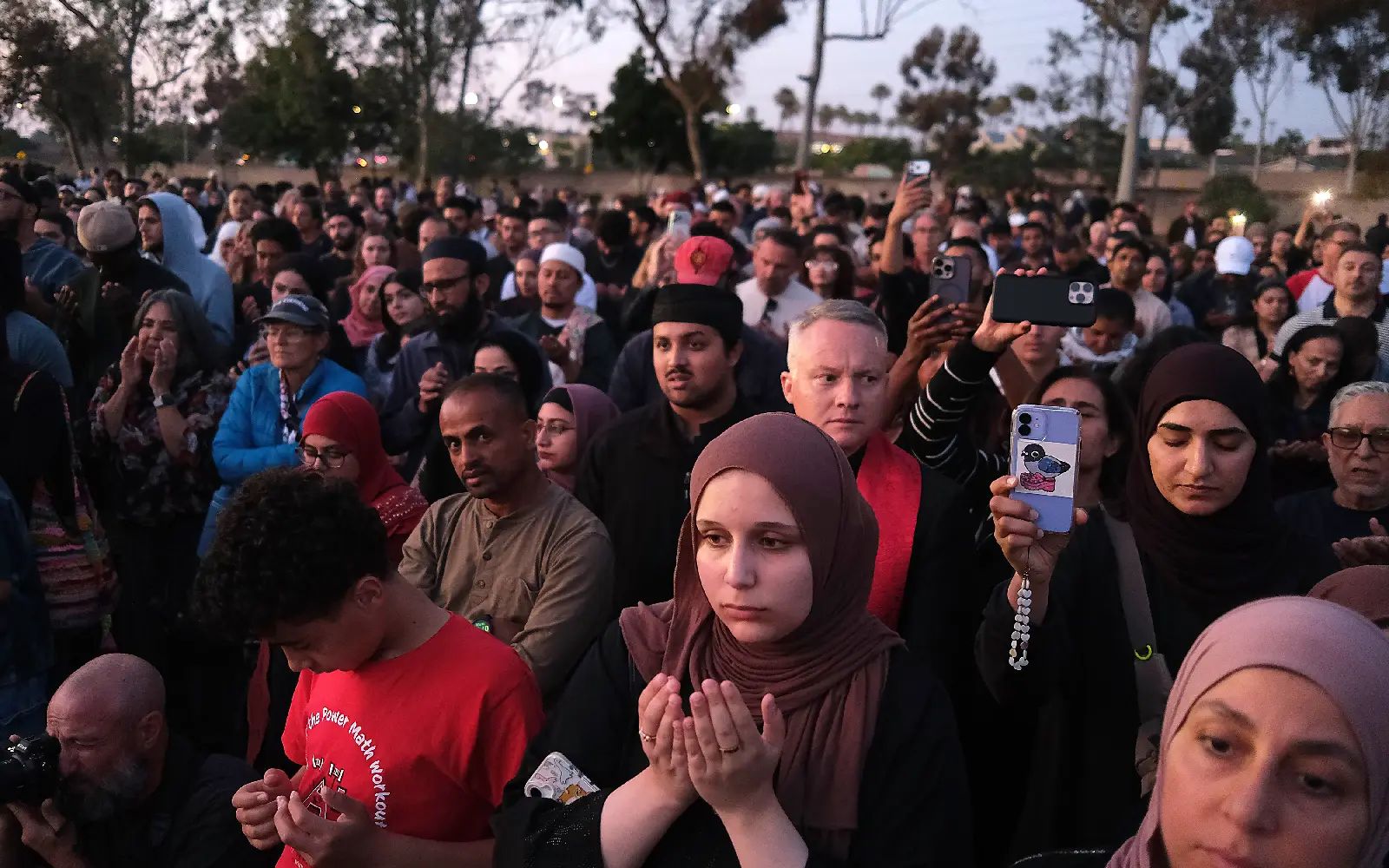 Mariam Eldegwy (C-R, foreground) prays at the conclusion of a vigil at a park for the victims of the Islamic Center of San Diego shooting; in San Diego, California, USA, 19 May 2026. Two teenage gunmen opened fire on 18 May, at the Islamic Center of San Diego in California, killing three men outside the mosque, including a security guard, before the two suspects were found dead, apparently from self-inflicted gunshot wounds, according to police. EPA/JOHN GASTALDO